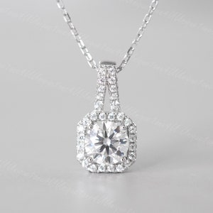May include: A silver pendant necklace with a large, round, clear gemstone surrounded by smaller, clear gemstones. The pendant is suspended from a delicate silver chain.