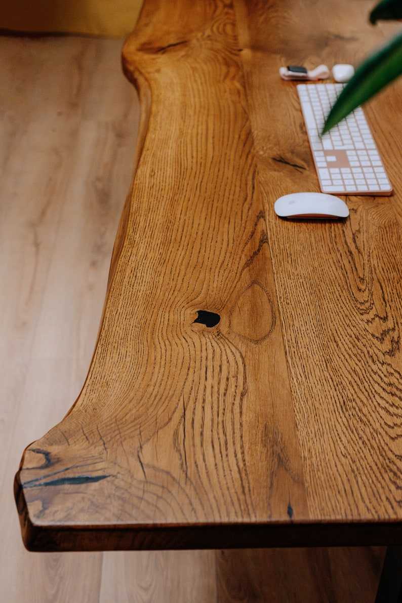 K&ouml;nnte beinhalten: Nahaufnahme eines Holzschreibtisches mit nat&uuml;rlicher Holzmaserung. Der Schreibtisch hat eine wei&szlig;e kabellose Tastatur und Maus darauf. Der Schreibtisch besteht aus einem einzigen St&uuml;ck Holz mit einer lebenden Kante.