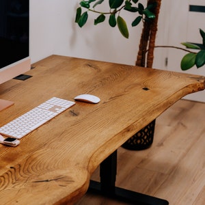 K&ouml;nnte beinhalten: Ein Holzschreibtisch mit einer wei&szlig;en Tastatur und einer wei&szlig;en Maus. Der Schreibtisch hat eine nat&uuml;rliche Holzoptik und ein Live-Edge-Design. Der Schreibtisch steht auf einem hellen Holzboden.