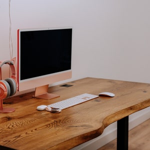K&ouml;nnte beinhalten: Ein Holzschreibtisch mit einer hellen Holzoptik. Auf dem Schreibtisch stehen ein Computermonitor, eine Tastatur und eine Maus. Links neben dem Monitor steht ein rosa Headset mit Katzenohren auf einem St&auml;nder.