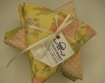 Peut inclure: Un lot de sachets en tissu en forme d'étoile avec des motifs floraux jaunes et pêche et des pois pêche. L'ensemble est noué avec un ruban couleur crème et comprend une étiquette blanche imprimée avec le texte Calico Basket et des coordonnées.