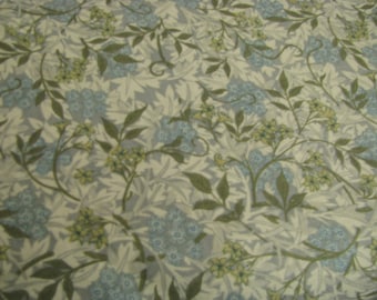 Könnte beinhalten: Stoff mit einem sich wiederholenden Blumenmuster. Das Design zeigt hellblaue und gelbe Blumen, grüne Blätter und graues Laub auf cremefarbenem Hintergrund. Das Muster ist detailliert und komplex und erzeugt eine Vintage- oder botanische Ästhetik.