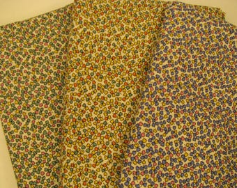 Peut inclure: Un morceau de tissu plié présentant un motif répétitif de petites formes de trèfles à trois feuilles. Le design comprend diverses combinaisons de couleurs de trèfles verts, jaunes, orange, roses et bleus sur un fond clair blanc cassé.