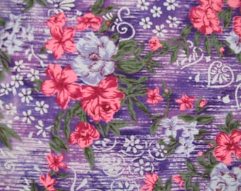 Peut inclure: Un tissu avec un fond violet présentant une texture de grain de bois horizontal. Le motif comprend des grappes de fleurs roses et blanches, des feuilles vertes et des motifs décoratifs en ligne blanche en forme de cœur et de cercle.