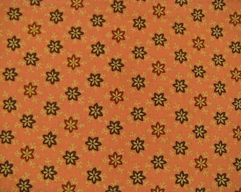 Peut inclure: Un tissu présentant un motif répétitif de fleurs marron foncé à six pétales avec des centres jaunes, entremêlées de petites brindilles beige clair, le tout sur un fond orange uni et sourd.