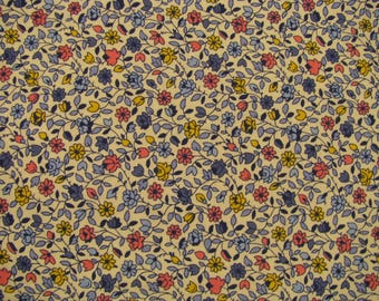 Peut inclure: Tissu floral avec un fond crème. Le motif présente de petites fleurs roses, jaunes et bleues, entremêlées de feuilles et de vignes vertes. Le design est dense et détaillé, créant une esthétique classique et vintage.