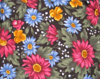 Könnte beinhalten: Ein Stoffmuster mit einer dichten Anordnung lebendiger Blumen auf schwarzem Grund. Das Design umfasst große magentafarbene Gänseblümchen, kleinere hellblaue Gänseblümchen und gelbe Stiefmütterchen, durchsetzt mit dunkelgrünen Blättern.