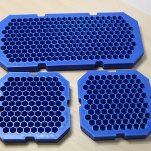May include: Three blue plastic honeycomb-shaped trays. The largest tray is rectangular, and the two smaller trays are square.