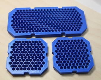 May include: Three blue plastic honeycomb-shaped trays. The largest tray is rectangular, and the two smaller trays are square.