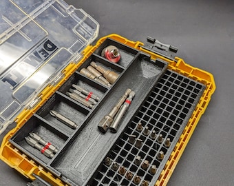 May include: A yellow and black plastic tool box with a clear lid. The box is open and contains a variety of drill bits and other tools. The box has a gridded section for storing small items.