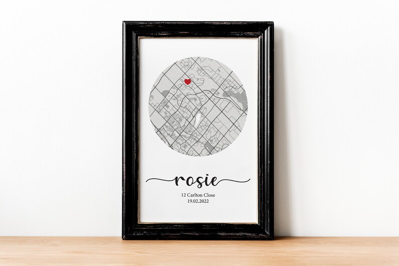 May include: A black framed print with a gray and white map of a city with a red heart marking a location. The text "rosie" is written in cursive below the map, followed by "12 Carlton Close 19.02.2022".