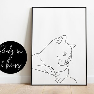 Puede incluir: Impresi&oacute;n de arte de l&iacute;nea de un gato sentado con la cabeza girada hacia un lado. La impresi&oacute;n es en blanco y negro y est&aacute; enmarcada en un marco negro.