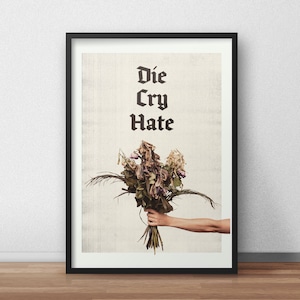 May include: A black framed poster with the text "Die Cry Hate" in a gothic font. A bouquet of dried flowers is held by a hand in the bottom right corner of the poster.