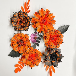 May include: Six orange and black paper flowers with a jack-o-lantern face design. The flowers are arranged in a circle on a white background.