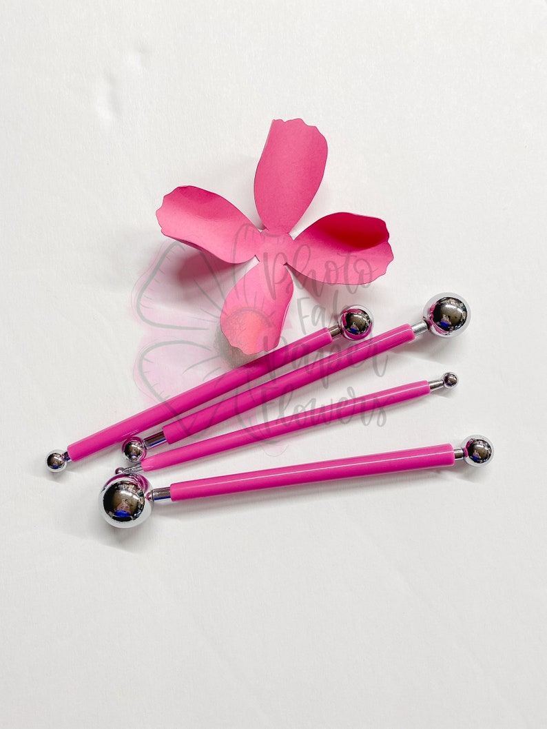 May include: Four pink handled tools with different sized ball-shaped tips. The tools are used for creating paper flowers.