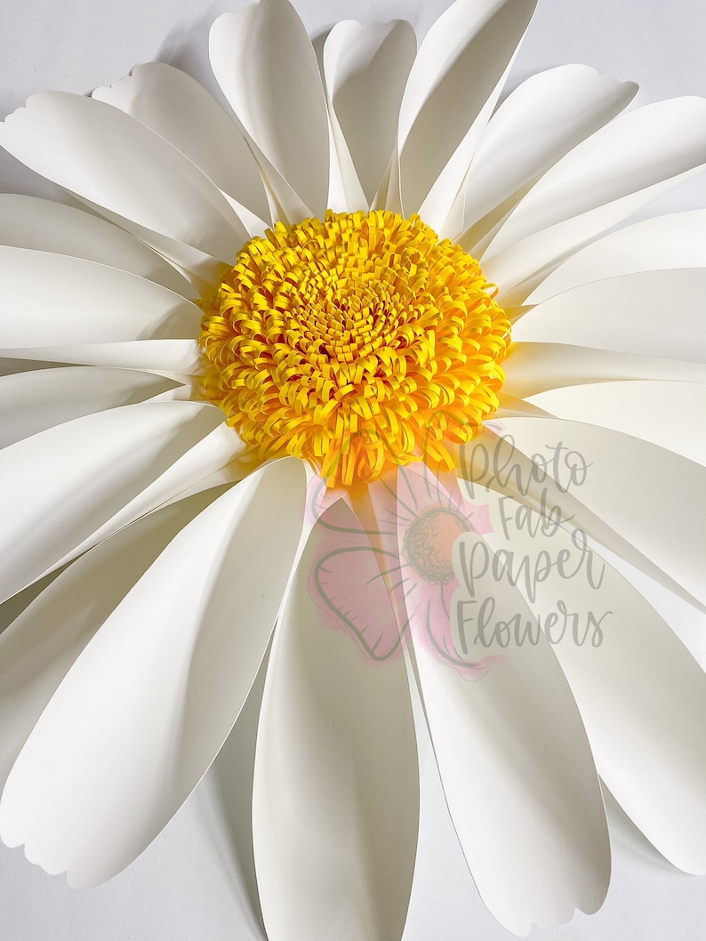May include: A large white paper daisy with a yellow center. The daisy is made of multiple paper petals and is a decorative craft.
