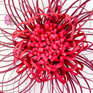 May include: A large, red paper flower with a layered, ruffled center. The flower is made from strips of paper that are curled and layered to create a 3D effect.