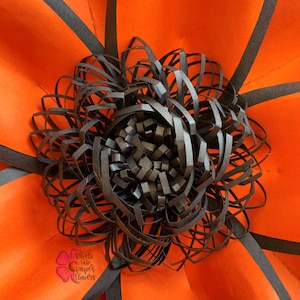 May include: A large, orange paper flower with black paper petals. The center of the flower is a black paper rosette.