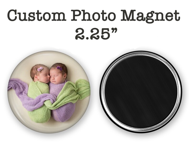 May include: Custom photo magnet featuring two newborn babies wrapped in purple and green blankets, sleeping and touching noses. The magnet is 2.25 inches in diameter.