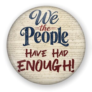 May include: A circular pinback button featuring a beige background with faint, repeating cursive script text. The words We the People are printed in large blue letters, while the words HAVE HAD ENOUGH! appear below in bold red text.