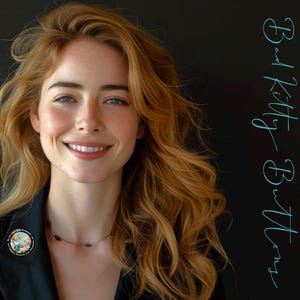 Op de afbeelding: Een vrouw met lang, golvend rossig haar glimlacht, draagt een zwarte blazer en een speld met een kleurrijk ontwerp. De tekst "Bad Kitty Buttons" staat verticaal in turquoise schrift op een zwarte achtergrond.