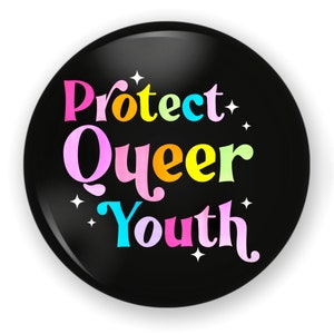 May include: A round, black button with the words "Protect Queer Youth" in colorful, rainbow-colored text. White star accents surround the text, creating a vibrant and eye-catching design.