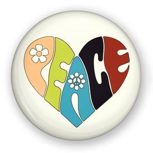 May include: A white button with a colorful peace sign in the shape of a heart. The peace sign is made up of the word "peace" with a flower and peace symbol in the center.