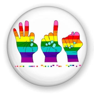 May include: A white button with a rainbow-colored hand gesture spelling out the word "Love" in American Sign Language. The hands are outlined in black and the button has a glossy finish.