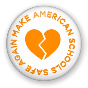 May include: A white button with orange text and a broken heart graphic. The text around the edge reads "AGAIN MAKE AMERICAN SCHOOLS SAFE." The heart is split down the middle. The button has a glossy finish.