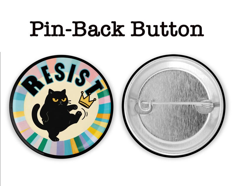 May include: A round pin-back button with a black cat kicking a gold crown. The word "RESIST" is written in black letters on a colorful background. The button's back is silver.