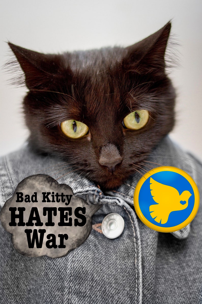 Pu&ograve; includere: Un gatto nero che indossa una giacca di jeans con un bottone a forma di segno della pace e un fumetto che dice "Bad Kitty HATES War".