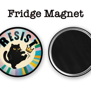 May include: A round fridge magnet with a black cat illustration kicking a gold crown. The word "RESIST" is in large letters. The magnet has a colorful striped background and the text "Fridge Magnet" at the top.