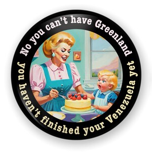 Op de afbeelding: Een ronde, zwarte knoop met een retro-illustratie van een vrouw en een kind die een taart versieren. De tekst rond de rand luidt: "No you can't have Greenland yet you haven't finished your Venezuela".