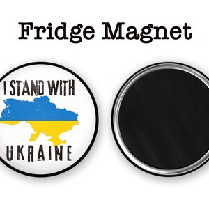 May include: A round fridge magnet with a white background and a blue and yellow outline of Ukraine. The text "I Stand With Ukraine" is printed in black above the outline and "UKRAINE" is printed in black below the outline.