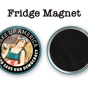 Może przedstawiać: Dwa okrągłe magnesy na lod&oacute;wkę. Jeden ma turkusową obw&oacute;dkę i napis "WAKE UP AMERICA VOTE TO SAVE OUR DEMOCRACY". Zawiera ilustrację kobiety w niebieskiej sukience. Drugi magnes ma czarną powierzchnię.