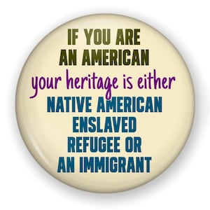 May include: A round, off-white button with the text "IF YOU ARE AN AMERICAN your heritage is either NATIVE AMERICAN ENSLAVED REFUGEE OR AN IMMIGRANT" in various colors. The text is centered on the button.
