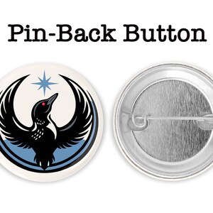 May include: A round pin-back button with a black bird design, a red eye, and a blue star. The bird has outstretched wings and is set against a white background with a blue border. The text "Pin-Back Button" is above the button.