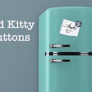 May include: A teal retro refrigerator with silver handles and a horizontal silver stripe. A small notepad with the word "Thanks" and a heart is attached with a paperclip. A round button is also attached to the refrigerator. The words "Bad Kitty Buttons" are on the left.