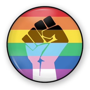 May include: A round button with a raised, glossy surface. The button features a rainbow-colored background with a black fist raised in the center. The fist is brown, symbolizing solidarity and unity.