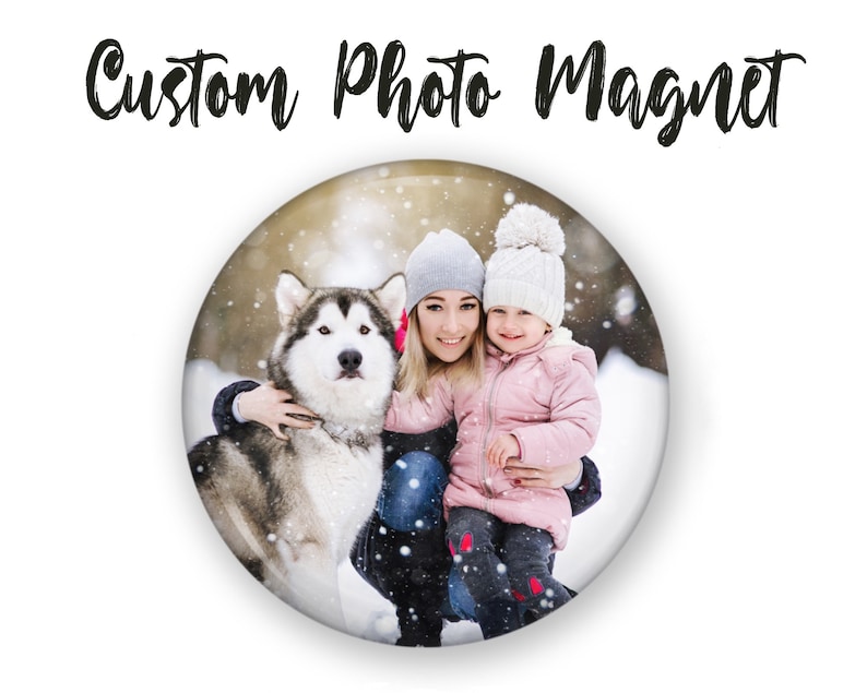 May include: A custom photo magnet featuring a woman and a young girl in winter clothing, smiling and holding a dog in a snowy setting.