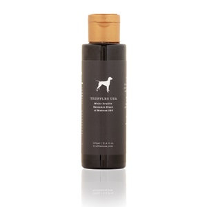 May include: A dark bottle of Truffles USA White Truffle Balsamic Glaze of Modena IGP. The label features a white dog silhouette and product information. The bottle has a gold cap and contains 3.4 fl oz of glaze.