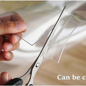 May include: A pair of silver scissors cutting a clear plastic sheet. The text "Can be cut" is visible in the image.