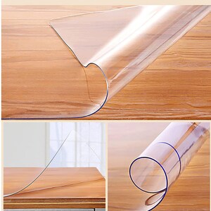 May include: Clear plastic table protector, rolled up to show its thickness and flexibility. The protector is designed to protect table surfaces from scratches and spills.