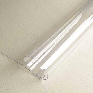 May include: A clear plastic table protector rolled up on a wooden surface.