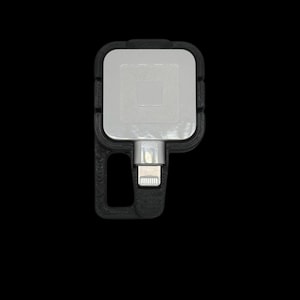 May include: A black plastic charging dock with a white square charging pad and a lightning connector.