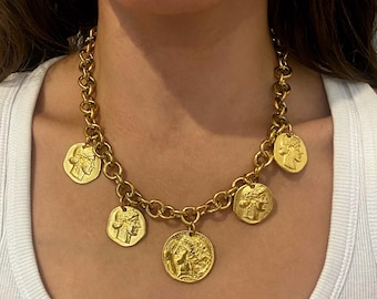 Könnte beinhalten: Goldfarbene Halskette mit einer klobigen Kette und mehreren Münzanhängern. Die Anhänger zeigen klassische Profil-Designs. Die Halskette ist ein Statement-Stück, das jedem Outfit einen Hauch von Vintage-Eleganz verleiht.