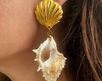 Könnte beinhalten: Goldene Muschelohrringe mit einem großen, goldenen, muschelförmigen Oberteil und einer kleineren, natürlichen Muschel, die darunter hängt.