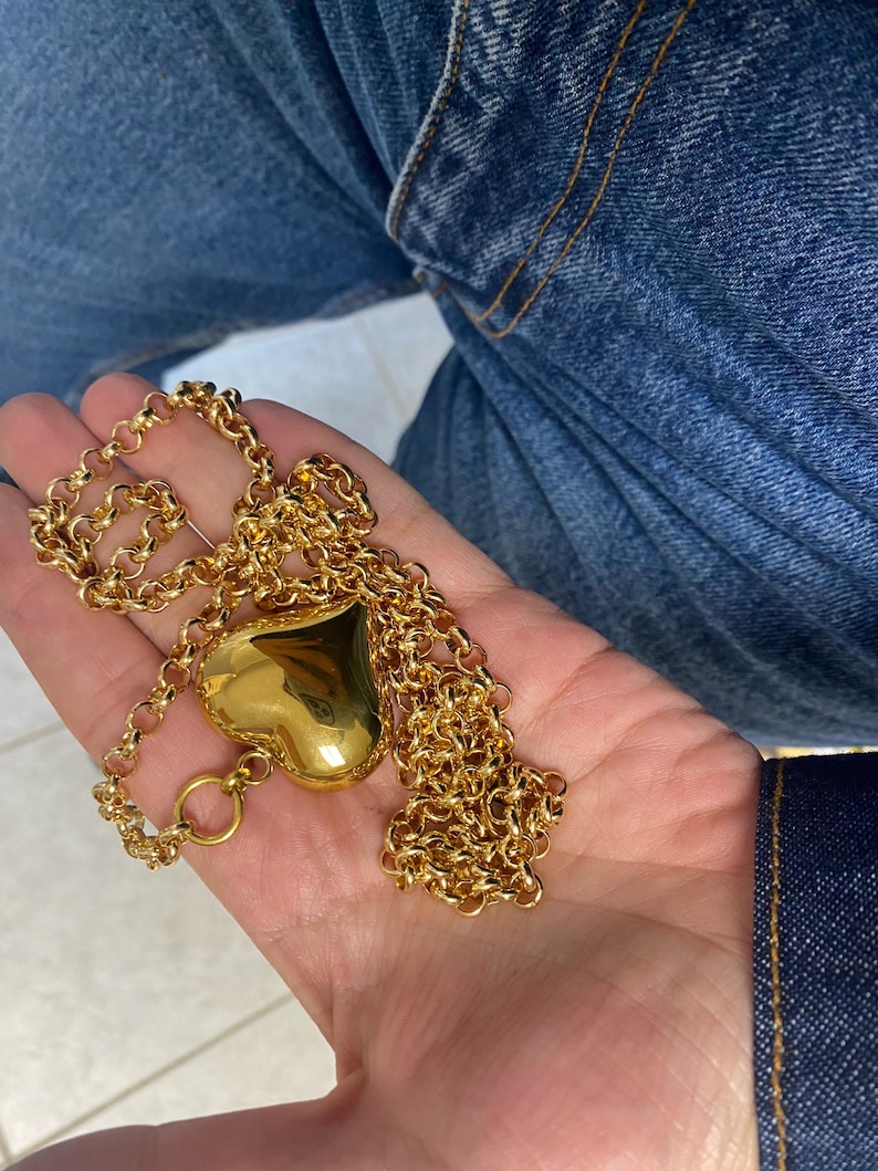 May include: A gold chain necklace with a large, heart-shaped pendant.