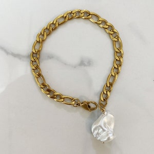 May include: A gold chain bracelet with a large, white, irregular pearl charm.