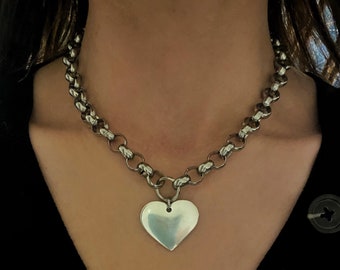 May include: A silver chain necklace with a large heart pendant.